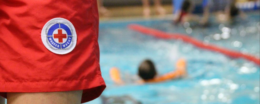 Träger einer Wasserwacht-Hose vor Schwimmbecken
