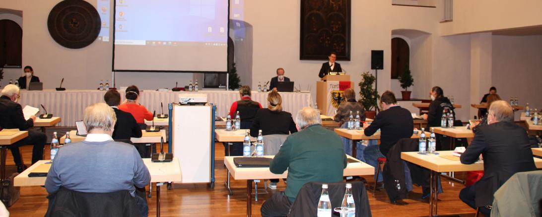 Stadträte sitzen im Stadtsaal Klösterle, vorne Leinwand und David Wittner am Pult