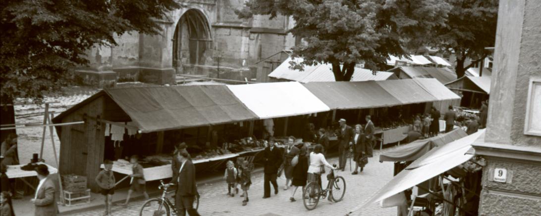 Das Bild zeigt Marktstände zur Nördlinger Mess‘ im Jahr 1949 vor der St. Georgs-Kirche.