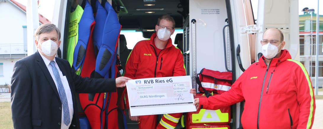 Das Bild zeigt Paul Ritter den Vorstandsvorsitzenden der RVB Ries, der einen Spendenscheck an die DLRG Nördlingen übergibt.