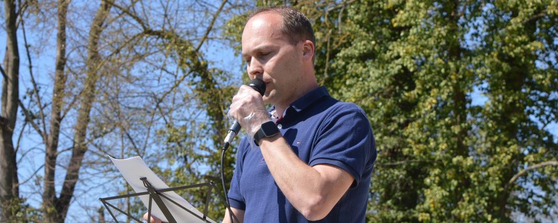 Mann mit Mikrofon vor Bäumen