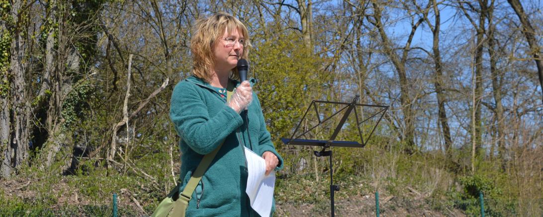 Frau mit Mikrofon vor Bäumen