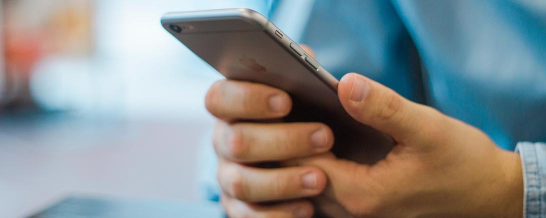 Das Bild zeigt Hände, die ein Smartphone halten.