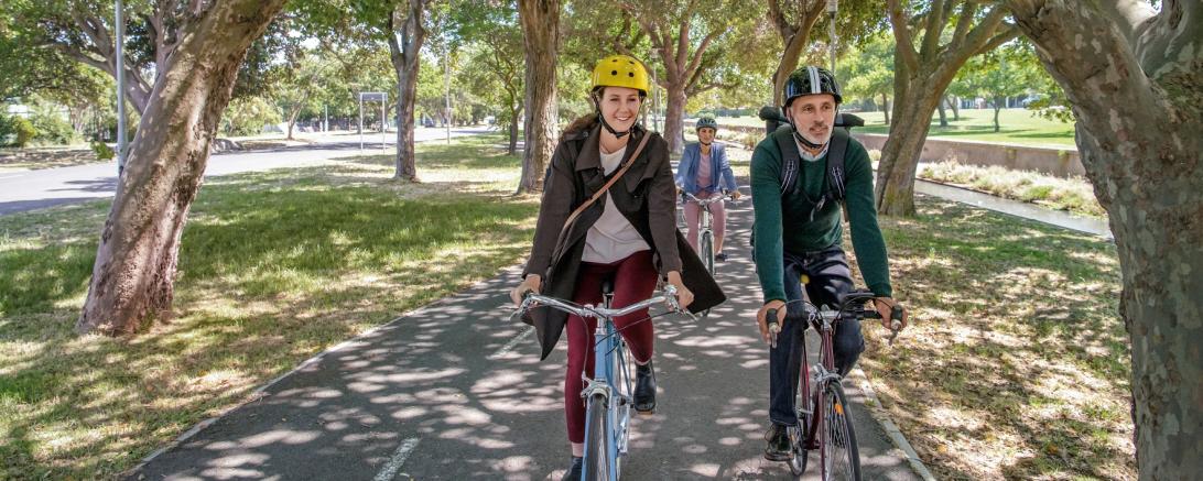 Das Bild zeigt zwei Menschen mit dem Fahrrad auf dem Weg in die Arbeit. 