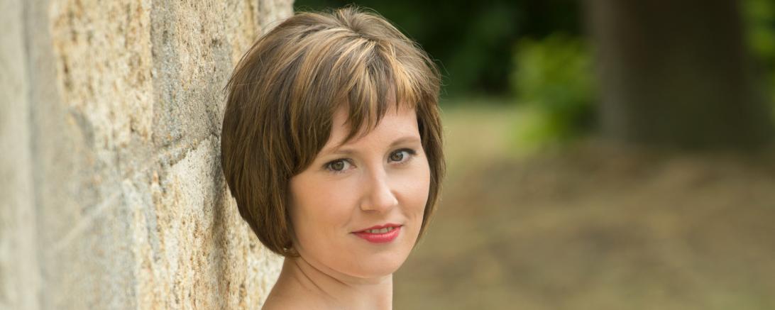 Frau im blauen Kleid lehnt an Mauer