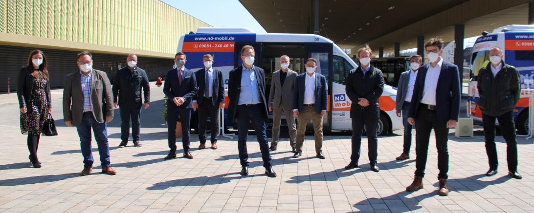 Zwölf Personen vor zwei Kleinbussen, mit Abstand aufgestellt