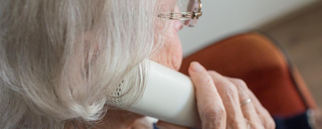 Das Bild zeigt eine Seniorin mit einem Telefon in der Hand.
