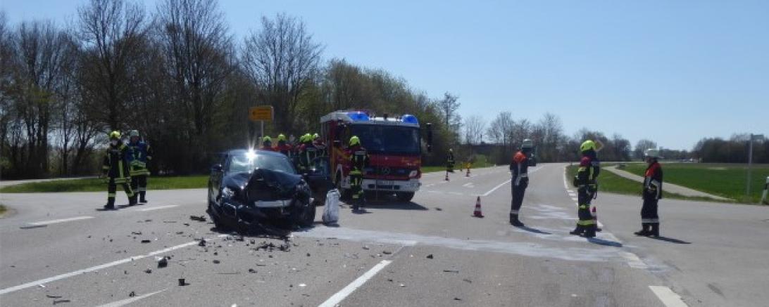 Feuerwehrleute und Feuerwehrauto bei einem Unfallwagen auf einer Straße