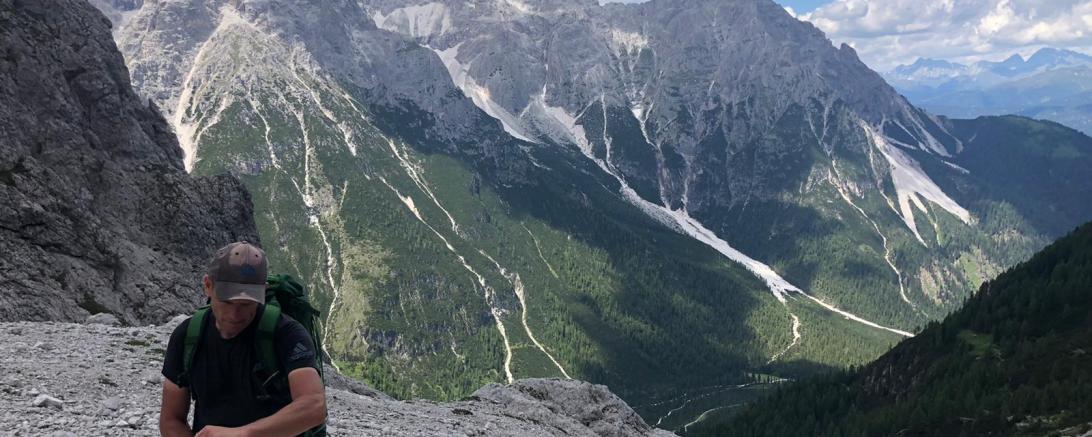 Das Bild zeigt ein Alpenpanorama, im Vordergrund einen Bergsteiger. 