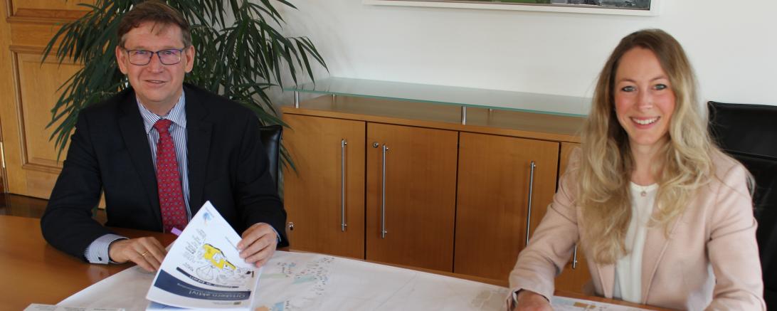 Das Bild zeigt Stefan Rößle mit Barbara Wunder am Tisch mit einem Bauplan. 