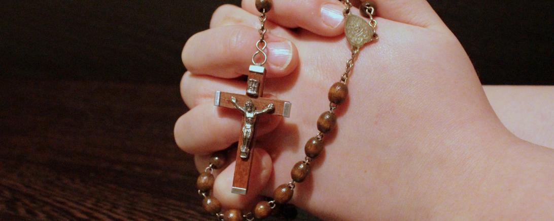 Das Bild zeigt gefaltete Hände und einen Rosenkranz 