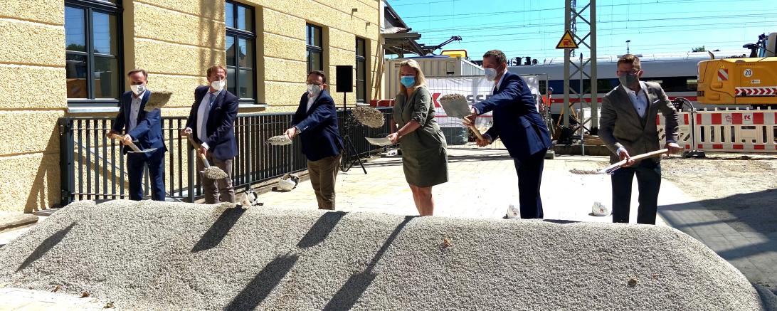 Sechs Personen schaufeln an einem Sandhaufen