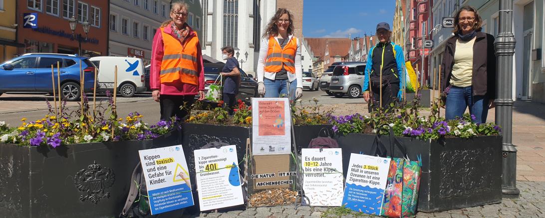 Vier Frauen stehen vor Blumenbeeten und machen Werbung für Nichtrauchen.