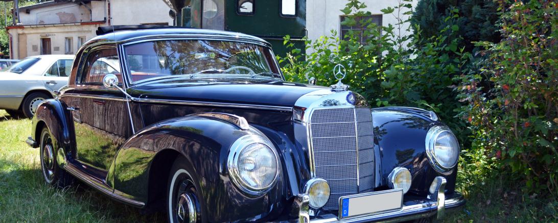 Auf dem Bild ist ein blauer Oldtimer zu sehen. 