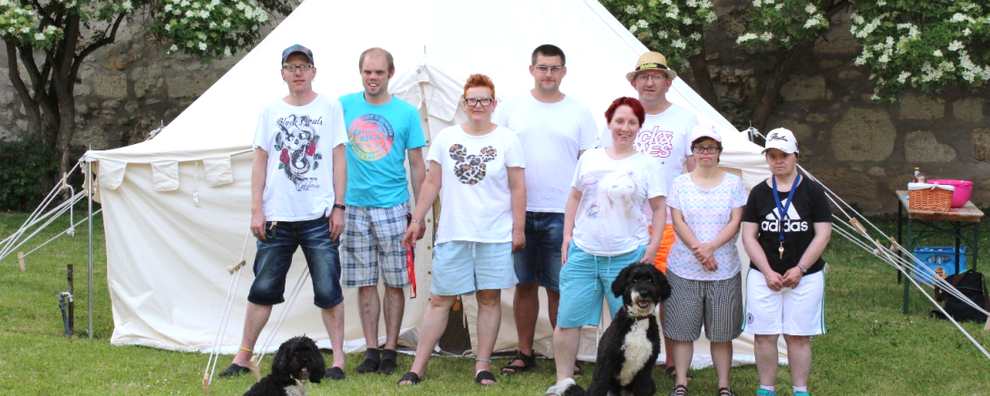 Das Bild zeigt Bewohnerinnen und Bewohner aus der Gruppe 3 vor einem ihrer Zelte