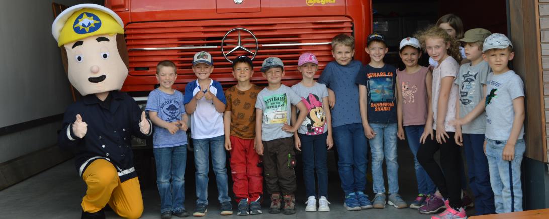 Kinder mit Feuerwehrmann Sam vor Feuerwehrauto