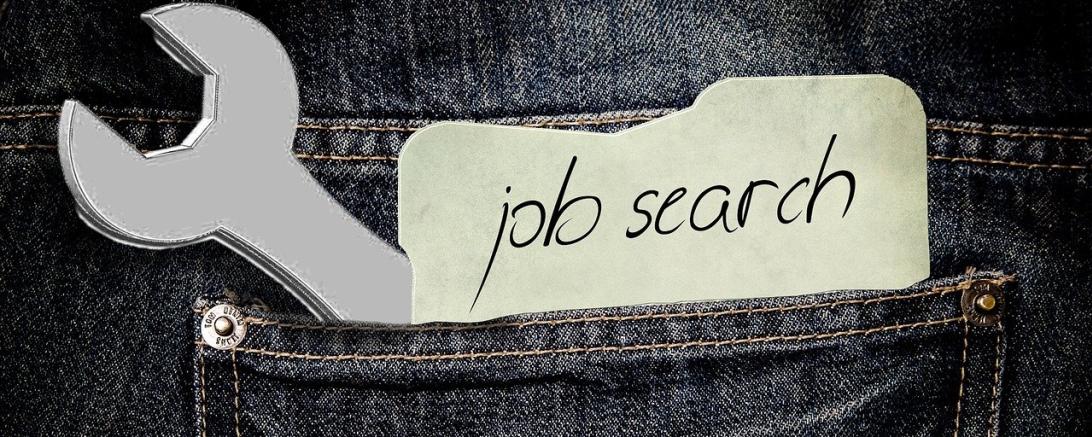 Es ist eine Hosentasche zu sehen, in der ein Zettel mit Jobsuche steckt.