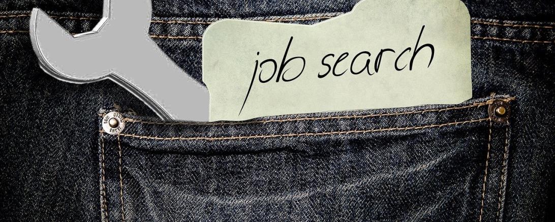 Es ist eine Hosentasche zu sehen, in der ein Zettel mit Jobsuche steckt.