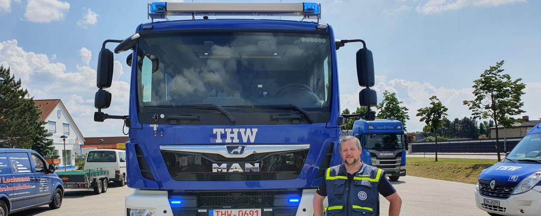 Mann steht vor THW-Fahrzeug