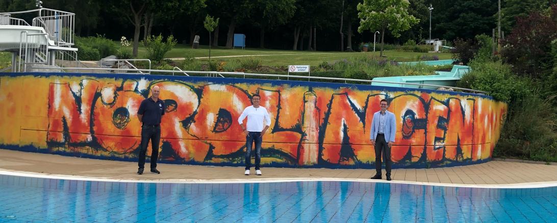 Wolfgang Balzer lässt mit seinem sommerlichen Kunstwerk die Betonwand am Nichtschwimmerbecken im Freibad Nördlingen aufleben. v.l.: Martin Gruber (Leiter Bäderbetriebe), Wolfgang Balzer (Künstler), Oberbürgermeister David Wittner