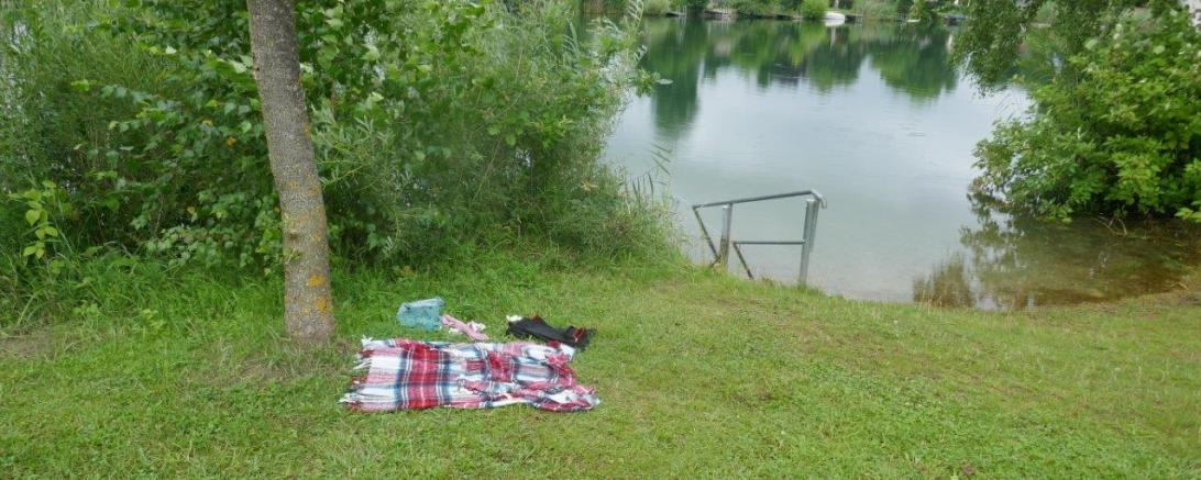 Seeufer mit Kleidung am Boden