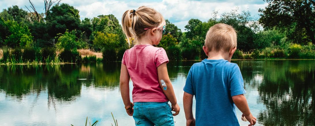 Das Bild zeigt zwei Kinder an einem See. 
