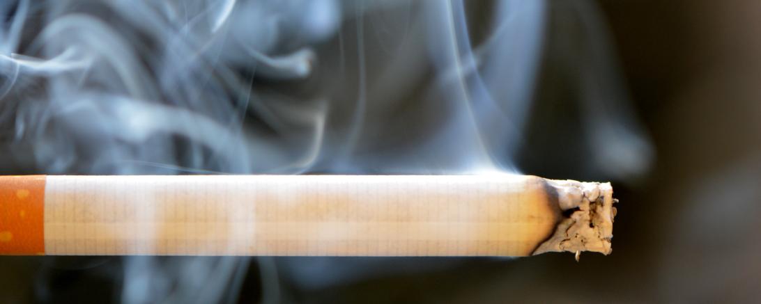 Brennende Zigarette mit Rauchschwaden