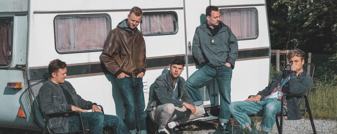 Fünf junge Männer vor Wohnanhänger