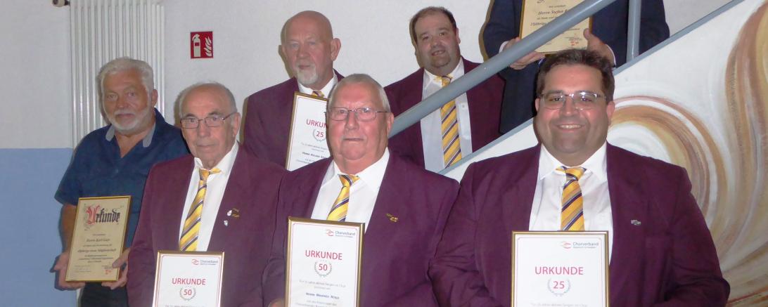 Männer in purpurnen Sakkos bei Treppe mit Urkunden