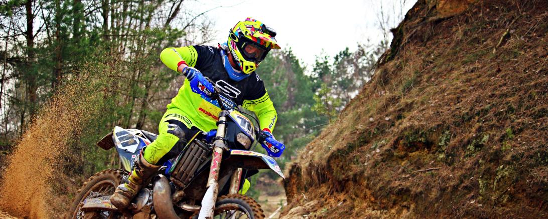 Motocrossfahrer fährt Bike auf sandiger Strecke