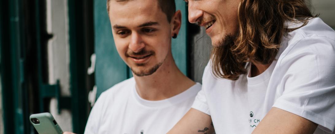 Das Bild zeigt zwei Männer mit Smartphone. 