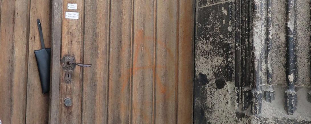 Tür einer Kirche, darauf ein "A" in einem Kreis gemalt