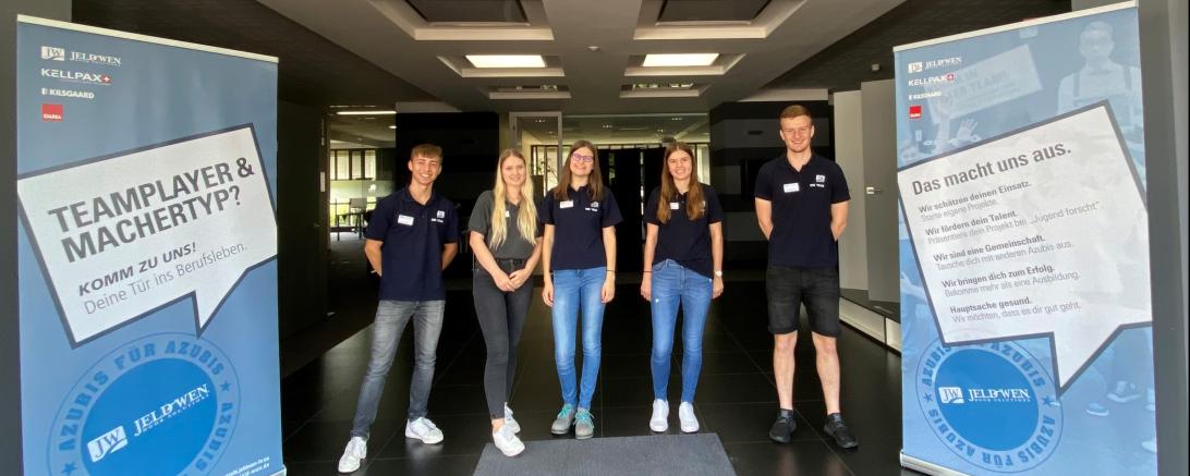 Zwei Herren und drei Damen zwischen zwei Jeld-Wen Roll-Ups.