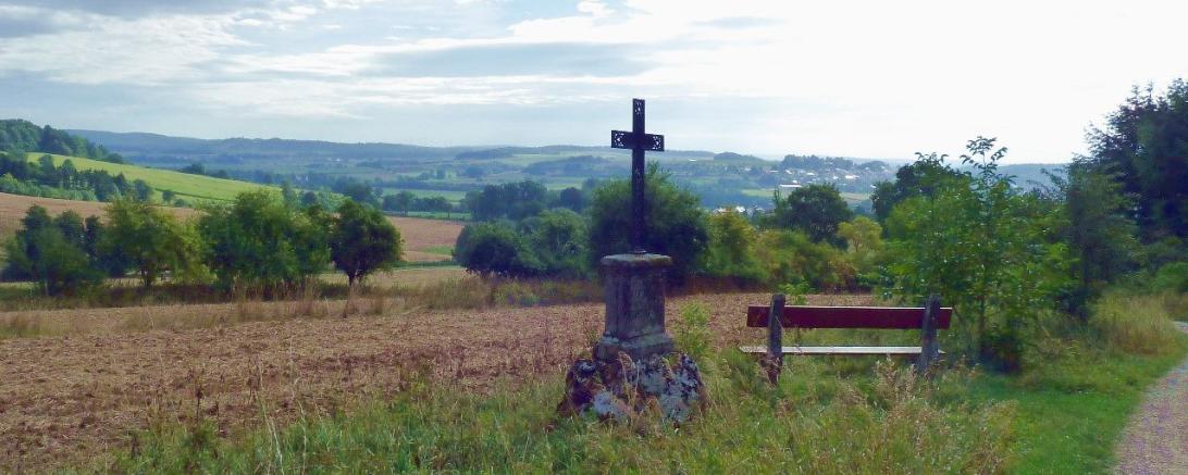 Blick in den Rieskrater, im Vordergrund eine Bank und ein Kreuz