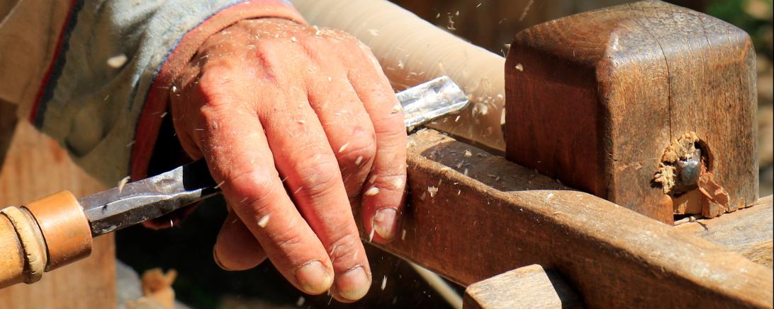 Hand mit Drechselmesser bearbeitet Werkstück an Drechselbank