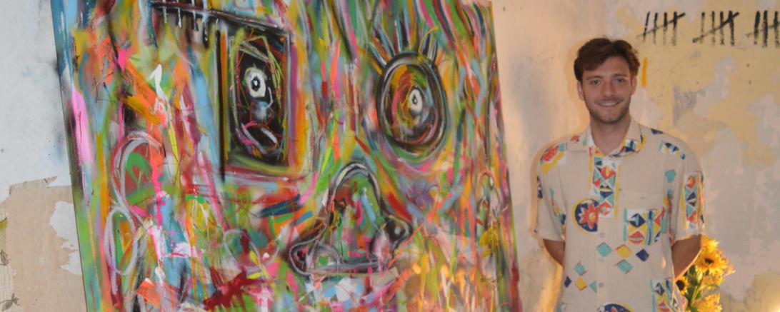 Auf dem Bild zu sehen der Künstler neben einem seiner Bilder. 