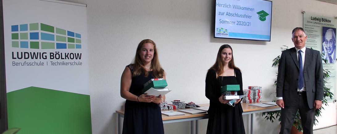 Zwei junge Frauen und ein Mann neben Ludwig-Bölkow-Berufsschule-Roll-Up