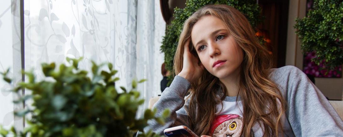 Das Bild zeigt eine junge Frau an einem Tisch sitzend. 