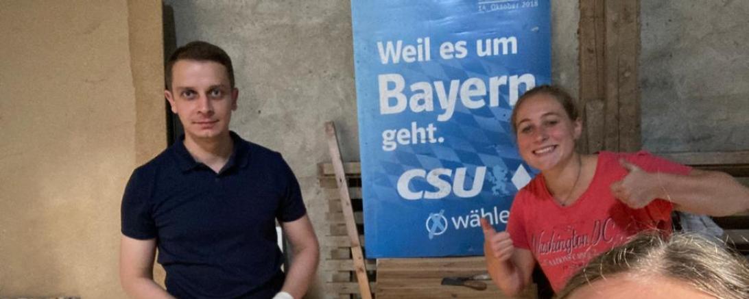 Mann und zwei Frauen vor CSU-Wahlplakat