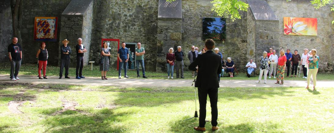 David Wittner, Rücken zur Kamera, hält Rede vor Personen vor Nördlinger Stadtmauer