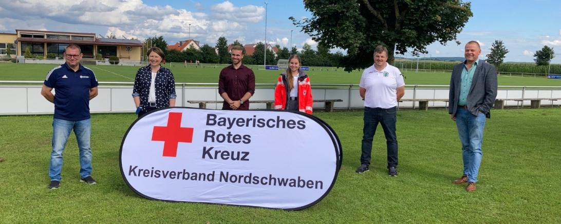 Sechs Personen mit BRK-Aufsteller auf Fußballplatz