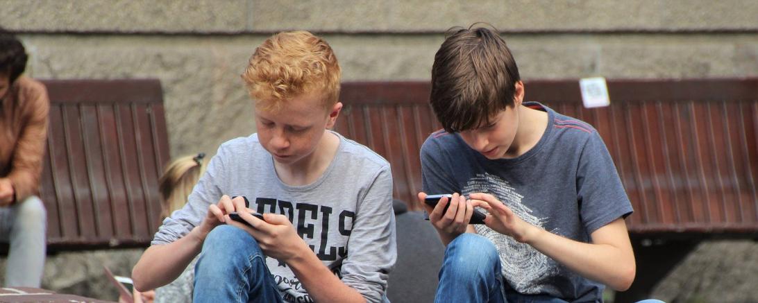 Das Bild zeigt zwei Jugendliche an ihren Handys. 
