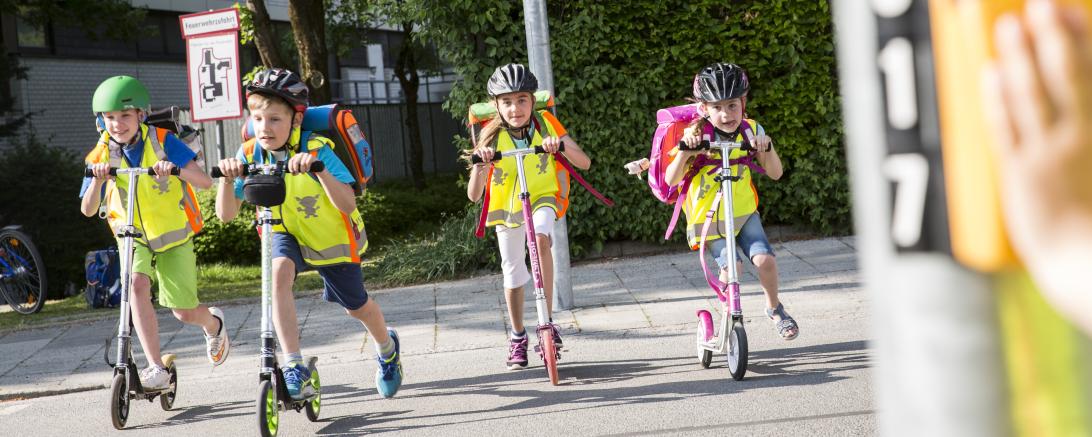 Kinder fahren mit Roller über Straße