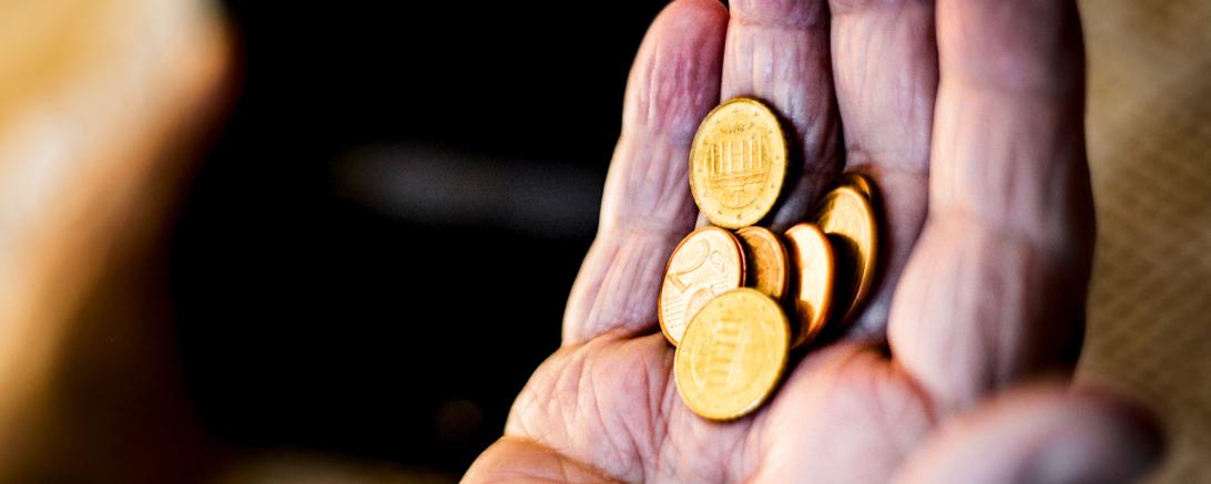 Hand eines alten Menschen hält mehrere Centmünzen
