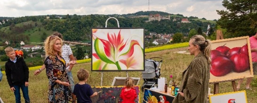 Auf dem Bild zu sehen Malgosia Neher und Besucher an der Staffelei am Leiterberg.