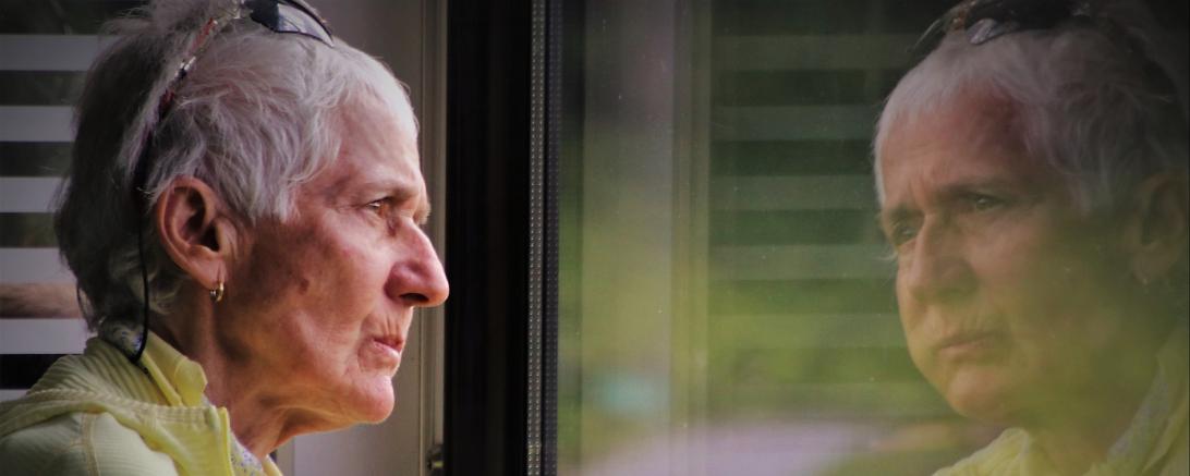 Alte Dame blickt durch Fenster