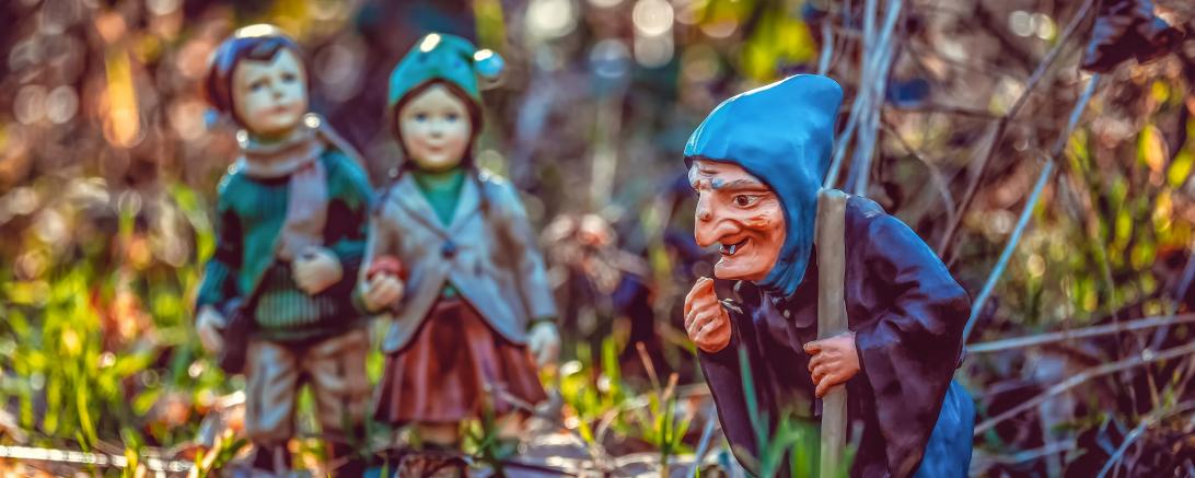 Tonfiguren von Hänsel, Gretel und der Hexe im Gras