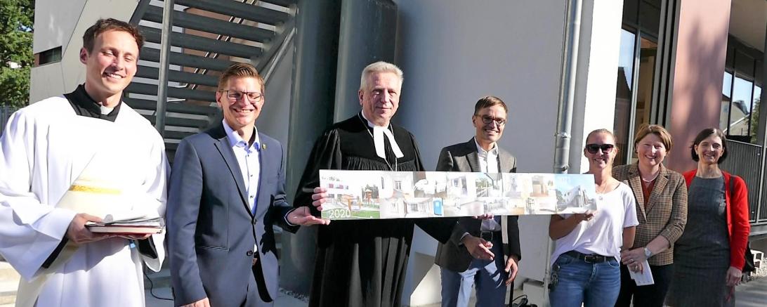 von links nach rechts Diakon Roland Kiechle, OB David Wittner, Dekan Gerhard Wolfermann hält zusammen mit Architekt Michael Leberzammer die Bildleiste die den Umbau dokumentiert, KiGa-Leiterin Annika Schneider, stv. Landrätin Claudia Marb, Präsidiumsmitglied KV Kathrin Wagner nach der Einweihungsfeier zur Erweiterung des Montessori-Kinderhauses am Nördlinger Kastanienbaum