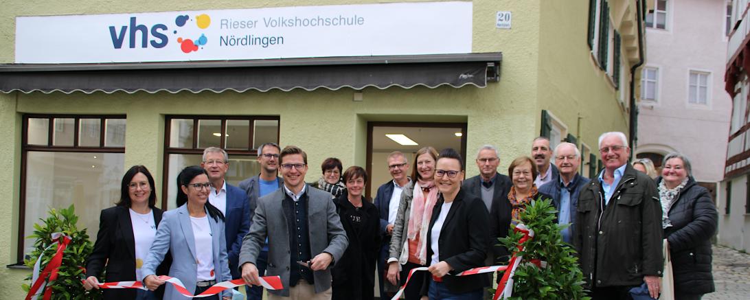 Gruppenbild mit 17 Personen bei Banddurchschneidung vor Geschäftsstelle der Rieser Volkshochschule