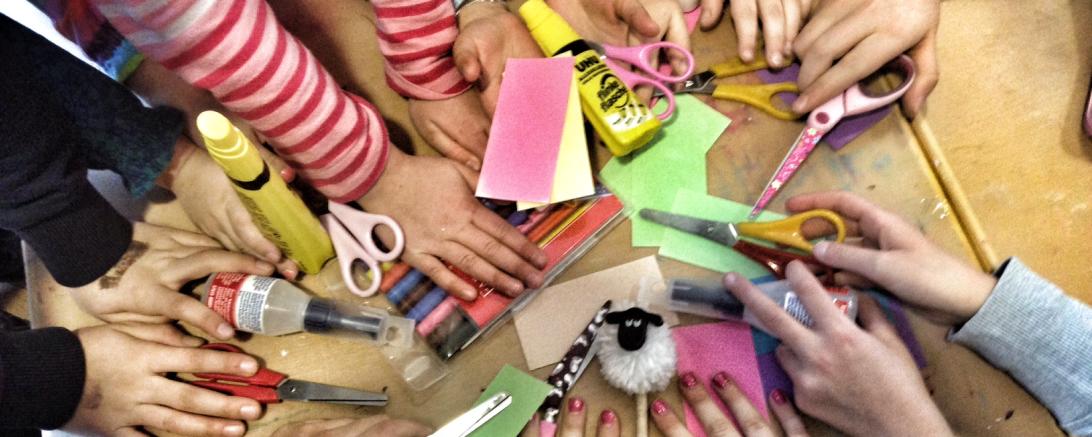 Kinderhände greifen sich Bastelmaterialien
